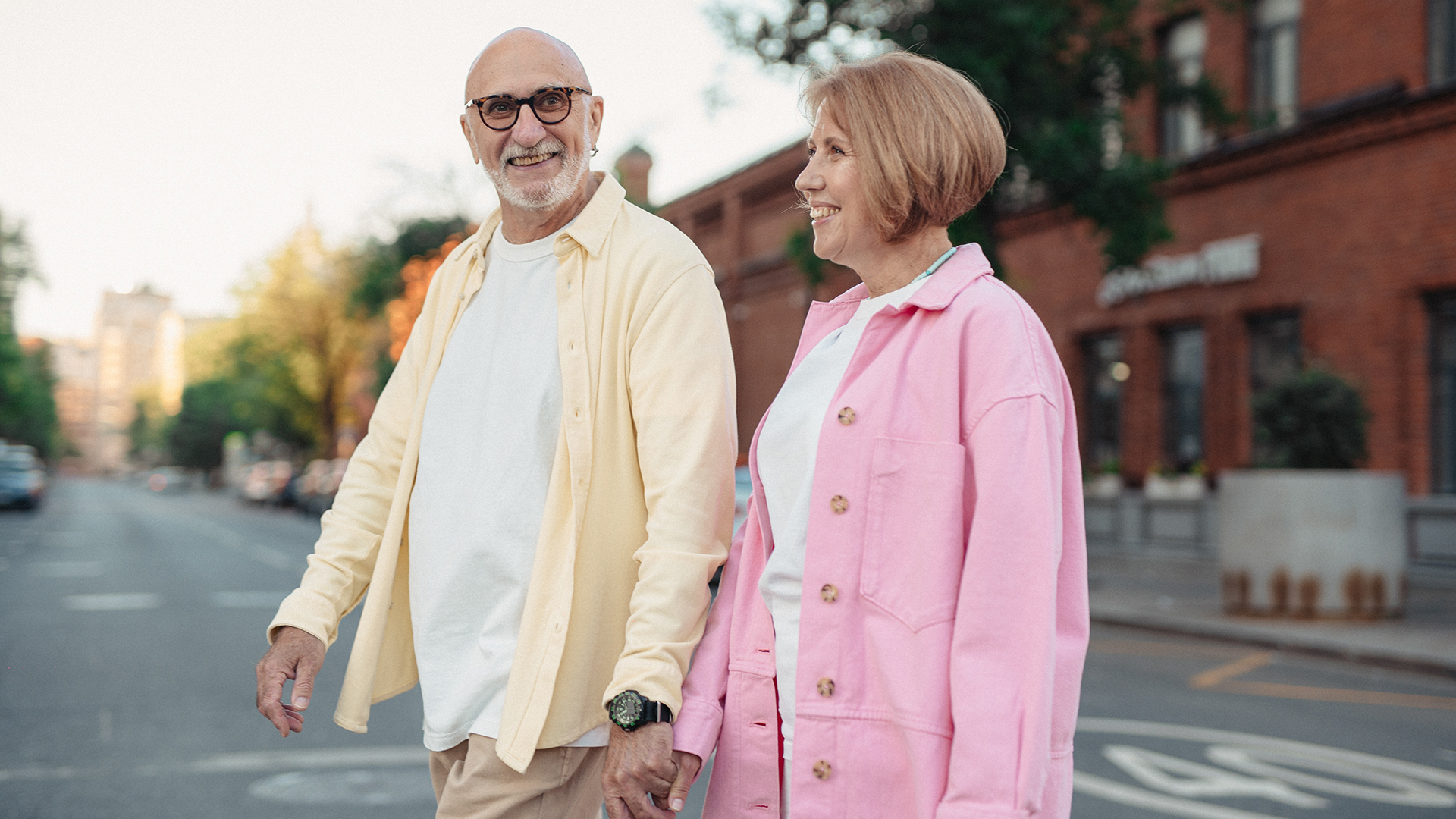 Older couple holding hands while crossing a city street