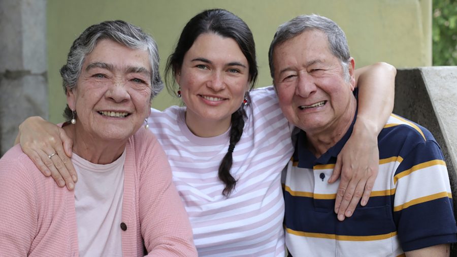 Adult daughter with her arms around her parents’ shoulders