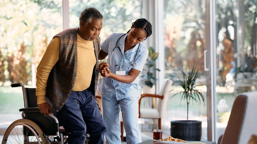 Nurse in an intermediate care facility assisting a patient into his wheelchair