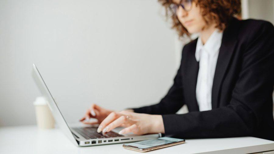 Female attorney working at table with laptop and cell phone